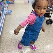 Zaniyah joined the competition — help win amazing prizes! toddler, child, denim_overalls, pink_shoes, store_aisle, curious_expression, bun_hairstyle, floor, socks, person, indoor, shopping, clothing, footwear, young_child, casual_wear, portrait, motion_blur, retail, cute