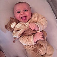 Ange participe au concours pour gagner de l'argent avec cette photo : baby, smiling, tongue_out, plush_toy, blanket, bed, soft_toys, cute, infant, child, happy, cozy, sleepwear, lying_down, indoors, person, toddler, comfort, playful, warm_colors