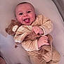 baby, smiling, tongue_out, plush_toy, blanket, bed, soft_toys, cute, infant, child, happy, cozy, sleepwear, lying_down, indoors, person, toddler, comfort, playful, warm_colors