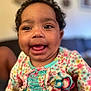 baby, child, smiling, curly_hair, floral_dress, colorful_clothing, happy, portrait, indoor, person, cute, closeup, infant, ruffles, playful, young_child, skin, face, eyes, mouth