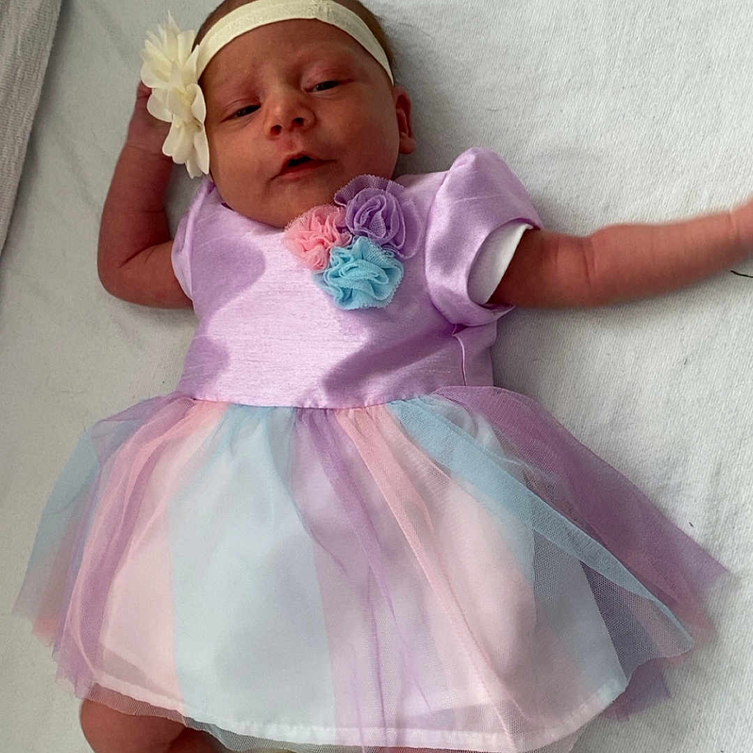 Ava joined the competition — help win amazing prizes! baby, blanket, child, cute, dress, flower_accessory, headband, indoor, infant, laying_down, newborn, pastel_colors, person, portrait, relaxed, small_hands, sock, soft_fabric, tiny_feet, tutu