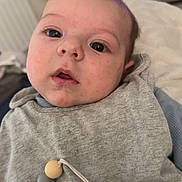 Zayyan participe au concours pour gagner de l'argent avec cette photo : baby, infant, face, pacifier, clothing, grey, beads, indoor, close_up, child, person, cute, expression, pacifier_clip, wooden_beads, silicone_beads, furniture, television, blurred_background, soft_lighting