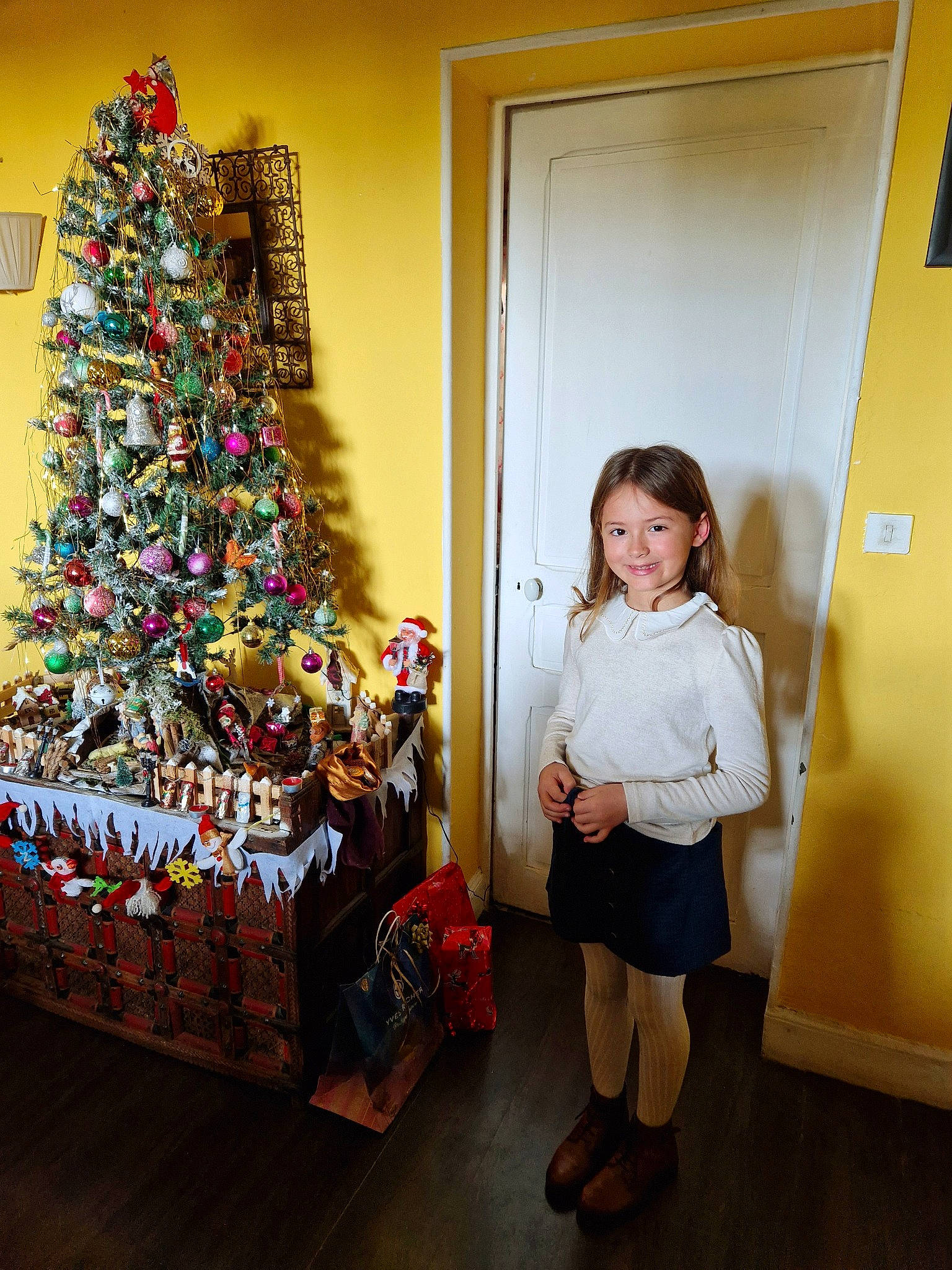 Livia participe au concours pour gagner de l'argent avec cette photo : boot, christmas, christmas_decoration, christmas_eve, christmas_ornament, christmas_tree, door, event, evergreen, fun, holiday, holiday_ornament, joy, living_room, ornament, person, plant, room, standing, toddler