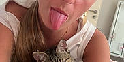 Beauty a rejoint le concours — aidez-le/la à gagner de superbes lots ! woman, cat, kitten, tongue_out, selfie, indoor, bed, white_clothing, long_hair, earrings, playful, cute, pet, striped_cat, relaxed, portrait, face, human, animal, cozy