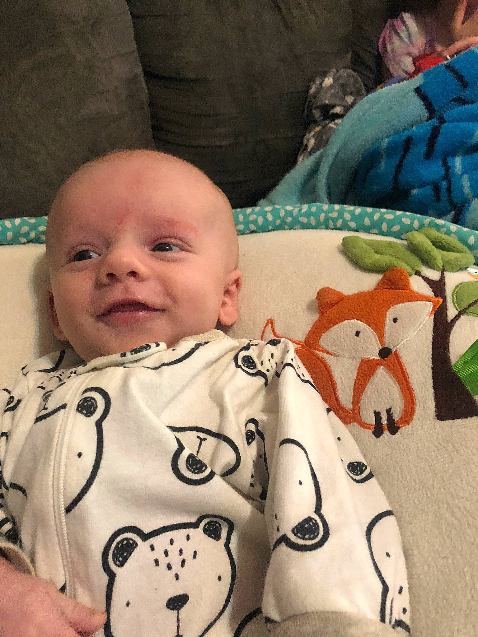 Conor is registered to the contest to win money with this photo: baby, baby_toddler_clothing, cheek, child, comfort, finger, happy, human, linens, mammal, nose, organ, pattern, people, person, skin, sleeve, smile, snapshot, textile