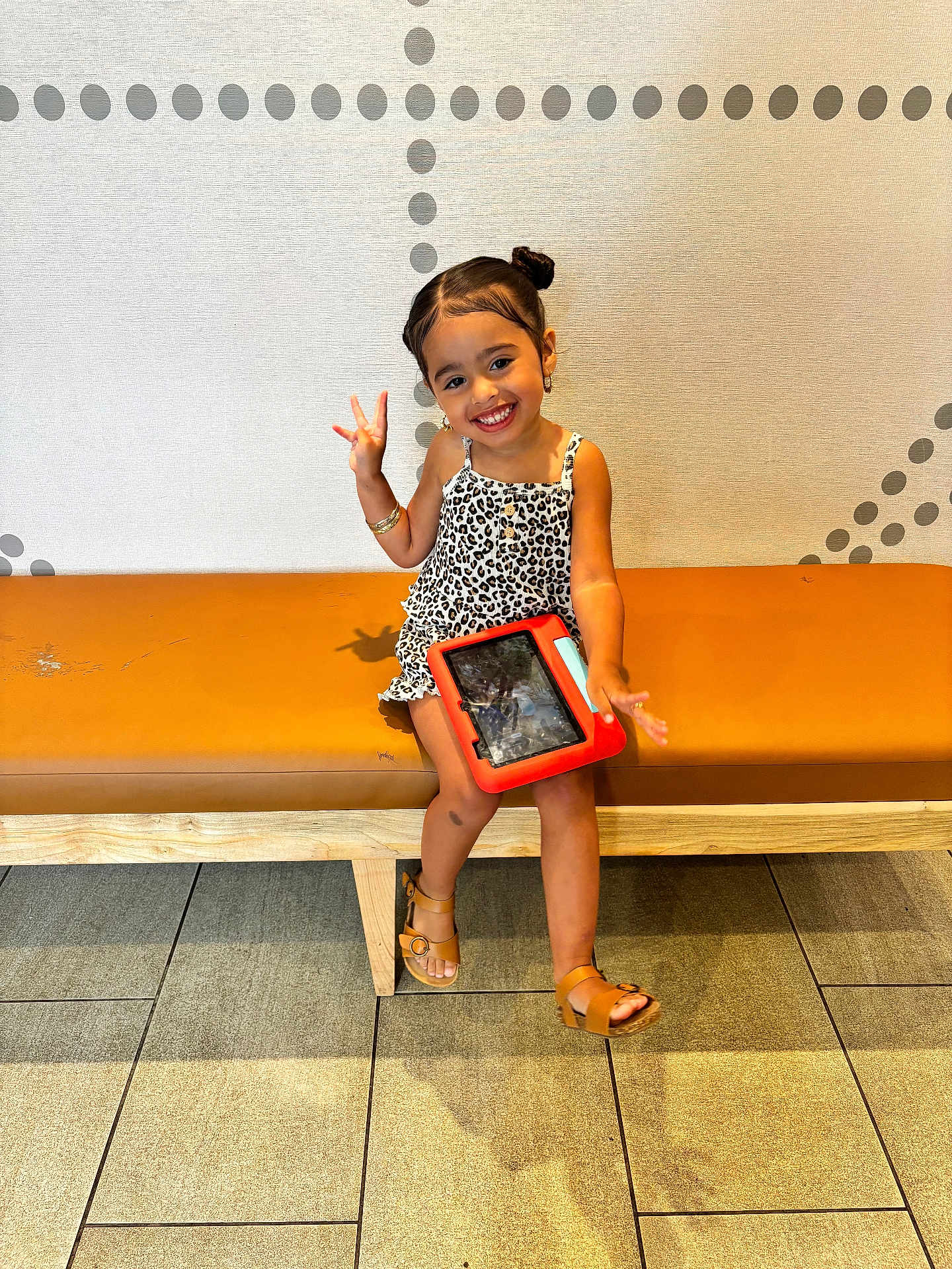 Sianny joined the competition — help win amazing prizes! child, girl, smiling, peace_sign, tablet, bench, sandals, brown_hair, hairstyle, wall_pattern, indoor, floor_tiles, casual_clothing, leopard_print, playful, happy, earrings, bracelet, modern_interior, sitting