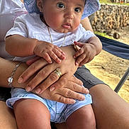 Adriel joined the competition — help win amazing prizes! baby, child, person, hat, white_clothing, hands, rings, bracelet, outdoor, nature, legs, shorts, skin, sitting, sunhat, curious, closeup, casual, daylight, adult