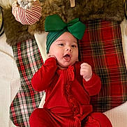Haisley joined the competition — help win amazing prizes! baby, infant, red_clothing, green_bow, headband, plaid_stockings, holiday_decorations, christmas, festive, cute, smiling, indoors, cozy, soft_texture, blanket, child, portrait, happy, celebration, seasonal
