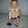 Paisley is registered to the contest to win money with this photo: baby, smiling, child, couch, furniture, indoors, clothing, footwear, sandals, happy, portrait, person, sitting, cute, yellow, patterned, embroidery, infant, face, skin