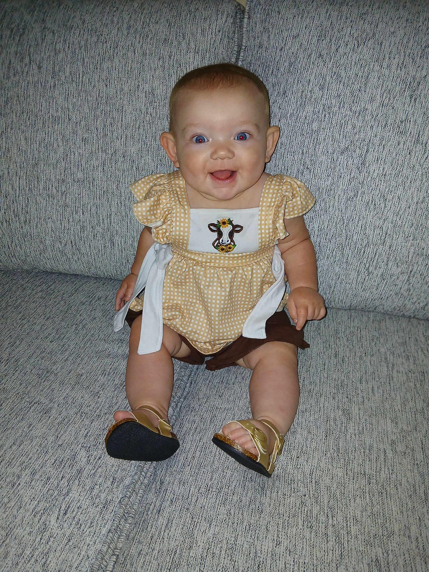 Paisley is registered to the contest to win money with this photo: baby, smiling, child, couch, furniture, indoors, clothing, footwear, sandals, happy, portrait, person, sitting, cute, yellow, patterned, embroidery, infant, face, skin
