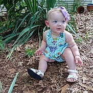 Paisley is registered to the contest to win money with this photo: baby, child, garden, plants, leaves, outdoor, blue_eyes, headband, purple_bow, dress, cartoon_characters, sandals, white_sandals, curious, sitting, nature, greenery, house_siding, summer, cute