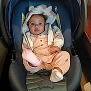 Nazarielle is registered to the contest to win money with this photo: baby, child, car_seat, hoodie, plush, cute, infant, pink, clothing, footwear, indoor, seat_belt, portrait, person, young_child, smiling, cozy, warm_clothing, baby_boy, car_seat_harness