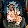 baby, child, car_seat, hoodie, plush, cute, infant, pink, clothing, footwear, indoor, seat_belt, portrait, person, young_child, smiling, cozy, warm_clothing, baby_boy, car_seat_harness
