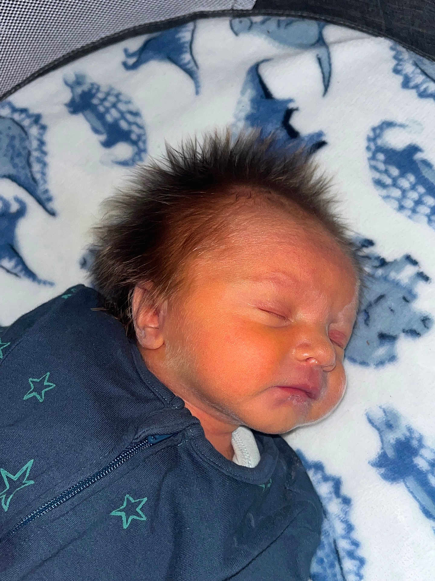 Freddie is registered to the contest to win money with this photo: newborn, baby, sleeping, hair, onesie, star_pattern, blanket, dinosaur_print, face, peaceful, infant, cute, portrait, child, soft, cozy, resting, indoors, closeup, young