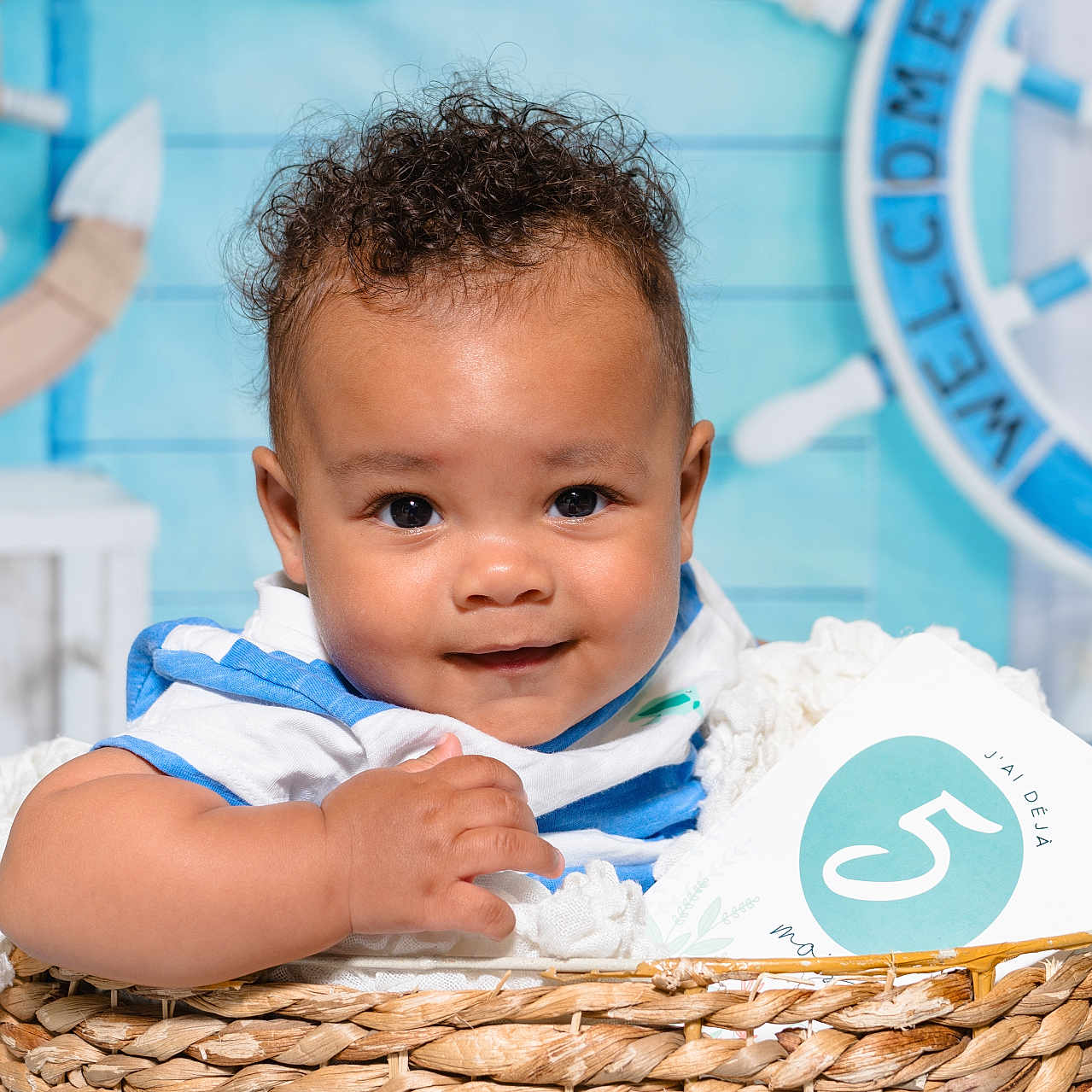 Shown a rejoint le concours — aidez-le/la à gagner de superbes lots ! baby, background, basket, blue_shirt, child, close_up, curly_hair, cute, decor, face, happy, indoor, infant, milestone_card, nautical, person, photography, portrait, smile, white_blanket