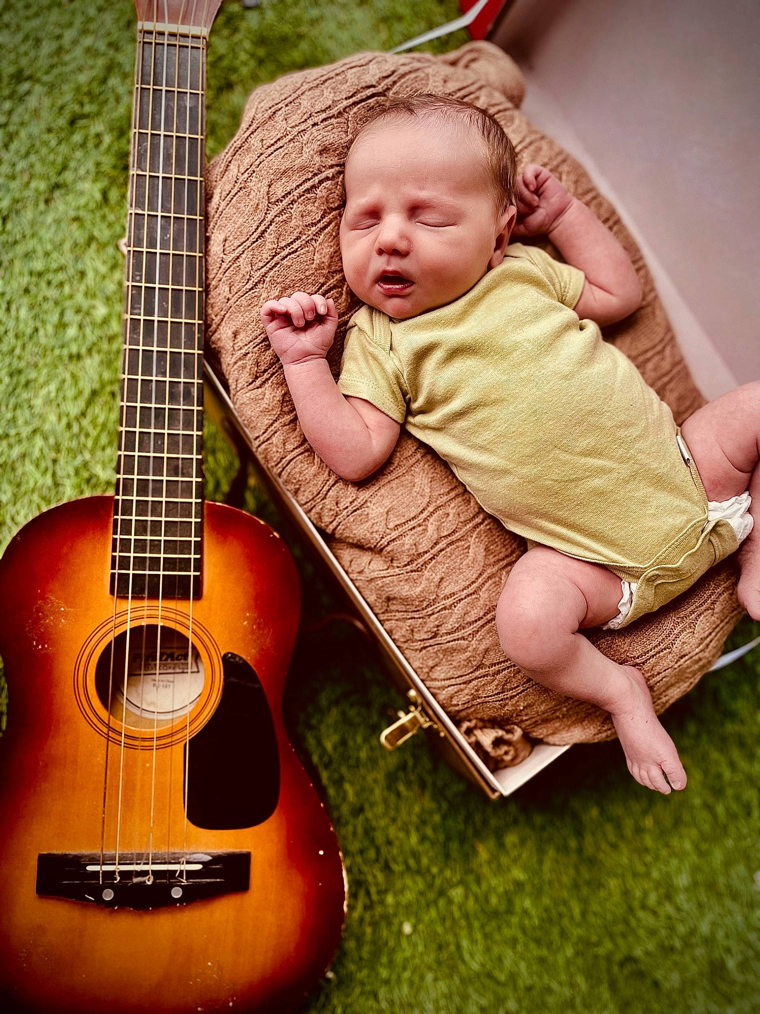 Myles is registered to the contest to win money with this photo: acoustic_guitar, baby, baby_toddler_clothing, folk_instrument, grass, guitar, guitar_accessory, happy, music, musical_instrument, musical_instrument_accessory, musician, people_in_nature, person, plucked_string_instruments, sitting, string_instrument, string_instrument_accessory, toddler, wood
