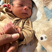 Sirius X is registered to the contest to win money with this photo: newborn, baby, infant, child, portrait, sleepy, face, hand, foot, tan_outfit, zipper, blanket, plush_blanket, cozy, indoors, close_up, lying_down, family, caregiving, soft_lighting
