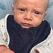 Gabin a rejoint le concours — aidez-le/la à gagner de superbes lots ! baby, newborn, infant, face, eyes, hands, bib, blanket, clothing, skin, portrait, close_up, looking_at_camera, cozy, soft_texture, blue_eyes, small_hands, lying_down, serious_expression, indoor