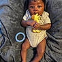 Ashtyn is registered to the contest to win money with this photo: baby, infant, blanket, teether, giraffe_toy, clothing, person, skin, hand, foot, face, lying_down, indoors, cute, child, newborn, soft_texture, blue_ring_toy, closeup, relaxing