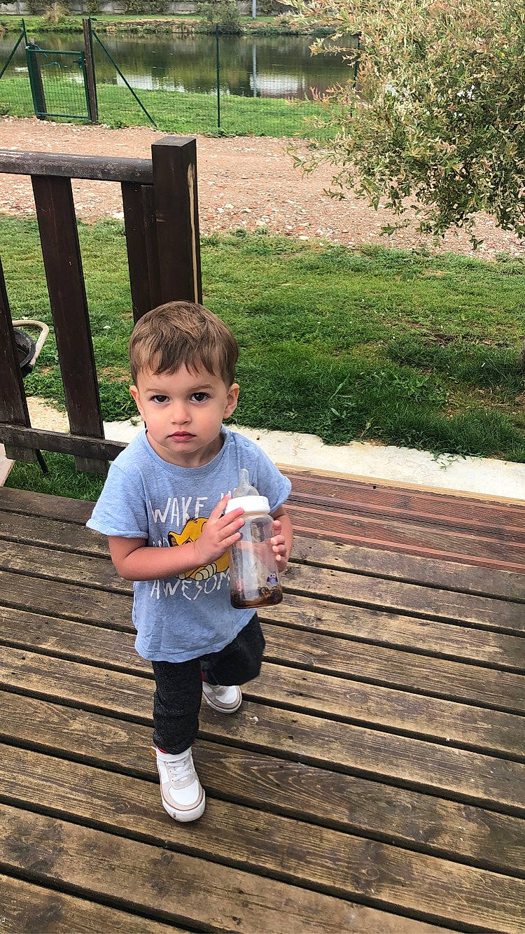 Lyam participe au concours pour gagner de l'argent avec cette photo : baby_toddler_clothing, child, deck, facial_expression, fun, grass, hair, happy, hardwood, leisure, people_in_nature, person, plant, play, recreation, sitting, t_shirt, thumb, toddler, tree