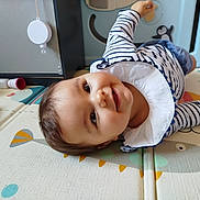 Albane a rejoint le concours — aidez-le/la à gagner de superbes lots ! baby, child, smiling, striped_shirt, play_mat, toy, indoor, happy, face, person, head, crawling, infant, playpen, colorful, cute, young_child, closeup, cheerful, toddler