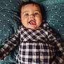 Albane a rejoint le concours — aidez-le/la à gagner de superbes lots ! baby, child, smiling, tongue_out, checkered_dress, patterned_cushion, blue_cushion, happy, cute, face, infant, lying_down, indoors, playful, young_child, person, clothing, cheerful, closeup, portrait