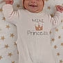 baby, smiling, headband, bow, onesie, blanket, star_pattern, infant, cute, happy, face, child, lying_down, soft_texture, cozy, apparel, portrait, young_child, indoors, sleepwear