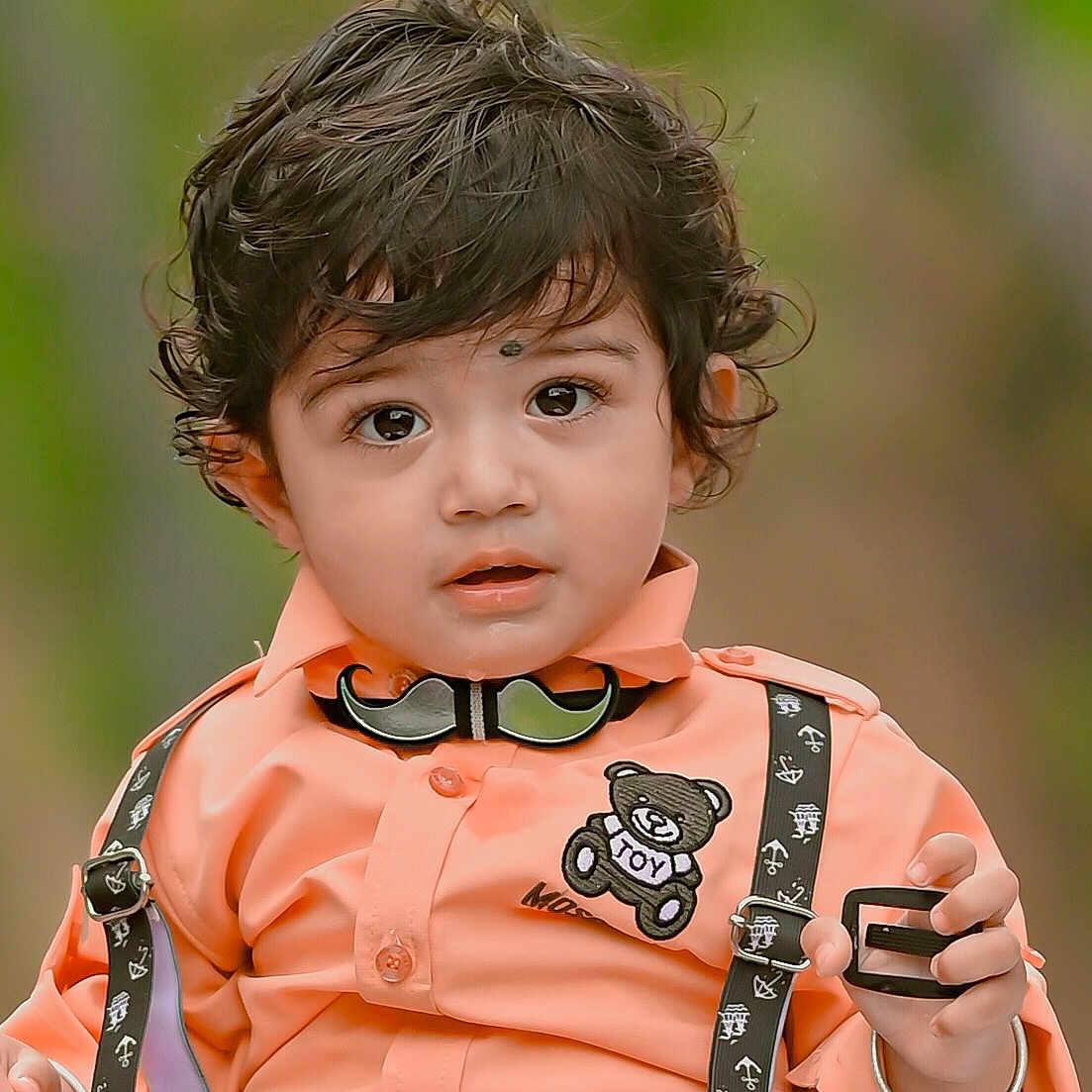 Ekaksh is registered to the contest to win money with this photo: accessory, baby, casual, child, clothing, curly_hair, cute, expression, eyes, face, fashion, hand, mustache_bow_tie, orange_shirt, outdoor, person, portrait, suspenders, toddler, young_child