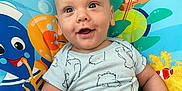 Isaiah joined the competition — help win amazing prizes! baby, child, onesie, blue, smile, play_mat, sea_creatures, cartoon, happy, infant, cute, face, clothing, sitting, indoor, bright, young, cute_expression, person, baby_toy