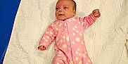 Jordan is registered to the contest to win money with this photo: baby, infant, pink_onesie, flower_pattern, blanket, white_blanket, blue_surface, smartphone, lying_down, newborn, cute, child, portrait, indoor, clothing, person, baby_girl, soft_texture, quilted, relaxing