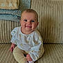 Elsie-Mae is registered to the contest to win money with this photo: baby, child, smiling, blue_eyes, sitting, couch, blanket, white_socks, ribbed_fabric, pastel_clothing, indoor, cozy, cute, portrait, happy, infant, comfortable, soft_texture, homedecor, drool