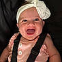 baby, child, smile, happy, headband, bow, pink_clothing, straps, harness, face, closeup, infant, cute, portrait, cheerful, young_child, human, sitting, apparel, expression