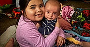 Daniel joined the competition — help win amazing prizes! affection, baby, blanket, carpet, child, comfort, couch, family, floor, hugging, indoor, infant, living_room, person, purple_blanket, red_toy, smile, striped_clothing, toy, young_child