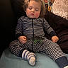 Joseph is registered to the contest to win money with this photo: toddler, sleeping, child, striped_pajamas, toy, dinosaur, couch, pillow, blanket, indoor, cozy, relaxed, nap, young_child, person, home, comfort, soft_lighting, face, hands