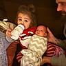 toddler, baby, bottle, swaddle, pajamas, family, adult, beard, couch, blanket, indoor, child, holding, comfort, bedroom, striped_clothing, red_clothing, white_clothing, relaxed, parent