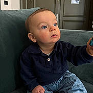 Gaspard a rejoint le concours — aidez-le/la à gagner de superbes lots ! baby, infant, child, blue_eyes, couch, sofa, living_room, portrait, sitting, navy_sweater, striped_pants, toy, hand, face, gaze, curious, indoor, furniture, skin, short_hair