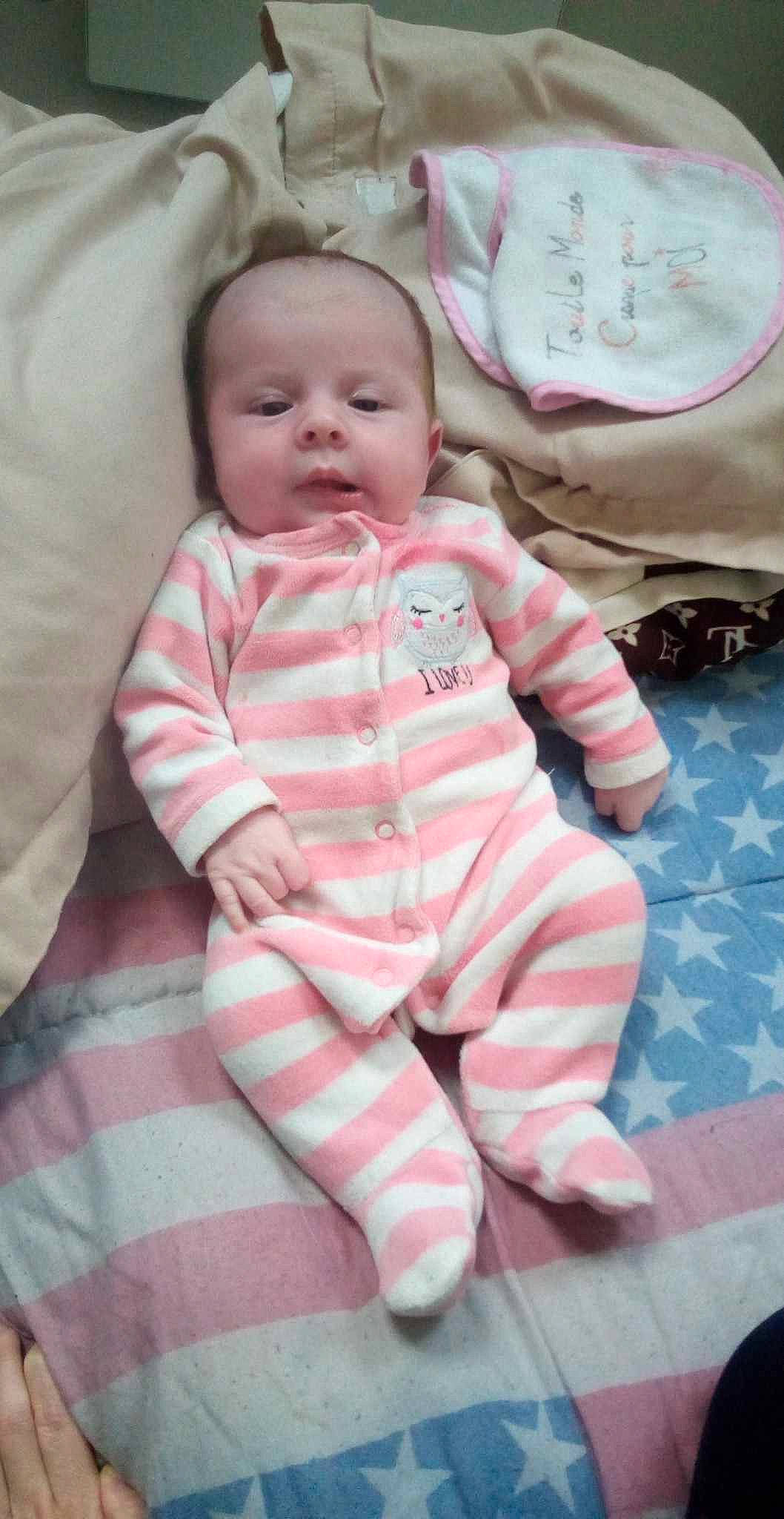 Chaynna a rejoint le concours — aidez-le/la à gagner de superbes lots ! baby, baby_toddler_clothing, cheek, child, comfort, face, flooring, fun, happy, linens, pattern, person, pink, room, sitting, skin, sleeve, smile, textile, toddler