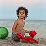 child, beach, sand, bucket, red_toys, curly_hair, ocean, sky, sandcastle, play, summer, outdoor, water, barefoot, toddler, daylight, vacation, fun, toy, nature