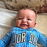 Rj is registered to the contest to win money with this photo: baby, bed, blue_onesie, child, cozy, cute, face, floral_pillow, hand, happy, indoor, infant, jordan, lying_down, person, portrait, skin, smiling, striped_clothing, tickling