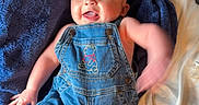 Rj is registered to the contest to win money with this photo: arms, baby, bed, blue_blanket, child, clothing, cute, denim_overalls, fabric, face, happy, head, indoors, infant, joyful, legs, person, portrait, smiling, textile