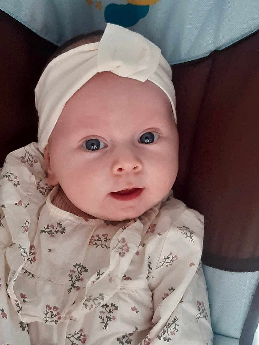 Giulia participe au concours pour gagner de l'argent avec cette photo : baby, infant, headband, floral_clothing, cute, portrait, face, eyes, child, young, soft_lighting, indoor, closeup, expression, adorable, person, fashion, sitting, head, skin