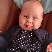 Giulia participe au concours pour gagner de l'argent avec cette photo : baby, infant, smiling, polka_dot, clothing, face, cute, child, seat, cushion, blue, navy, cardigan, playful, tongue_out, portrait, indoors, happy, person, cartoon