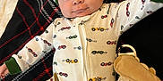 Jase is registered to the contest to win money with this photo: baby, infant, onesie, hat, blanket, plush_toy, toy, smiling, wide_eyes, lying_down, pattern, bed, cozy, pajama, closeup, face, portrait, adorable, car_prints, green_trim