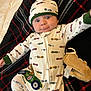 baby, infant, onesie, hat, blanket, plush_toy, toy, smiling, wide_eyes, lying_down, pattern, bed, cozy, pajama, closeup, face, portrait, adorable, car_prints, green_trim