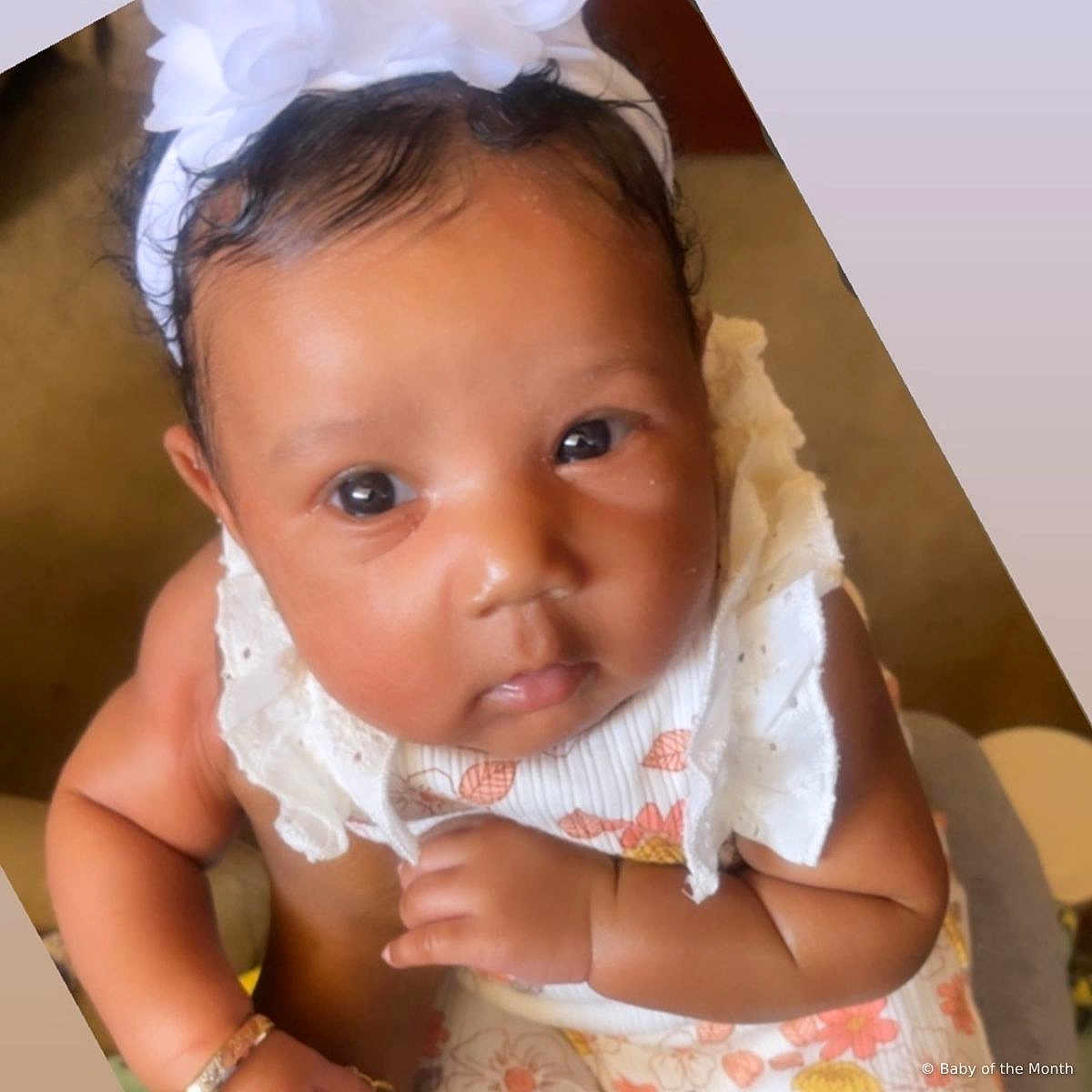 Kamora is registered to the contest to win money with this photo: baby, infant, child, headband, flower, dress, cute, closeup, portrait, skin, hand, arm, indoors, person, young, curious, holding, fashion, accessory, adorable