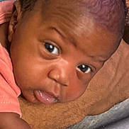 Azalea is registered to the contest to win money with this photo: baby, infant, close_up, face, eyes, skin, curly_hair, expression, resting, soft_surface, person, child, peach_clothing, portrait, indoors, newborn, cute, young, head, lying_down