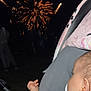 baby, blanket, celebration, clothing, colorful, dark, ear, event, face, fireworks, hand, infant, light, night, outdoor, pacifier, people, sky, stroller, toy