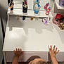 toddler, child, mirror, reflection, vanity_table, lipstick, toy, flower, hands, chair, furniture, pink_clothing, baby, indoor, curious, person, skin, table, cosmetics, small_objects