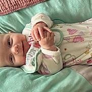 Harper is registered to the contest to win money with this photo: baby, infant, smile, face, hands, onesie, bib, cushion, blanket, pastel_colors, soft_texture, cute, lying_down, cozy, indoor, child, person, happy, relaxing, closeup