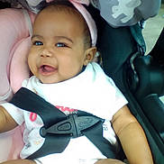 Jaiyana joined the competition — help win amazing prizes! baby, child, car_seat, pink_headband, smile, happy, infant, safety_harness, cute, indoor, seated, clothing, closeup, person, headwear, soft_toy, baby_girl, cheerful, portrait, seat_belt